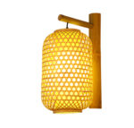 Cette applique est en rotin et en forme de lanterne , elle placée sur un fond blanc.