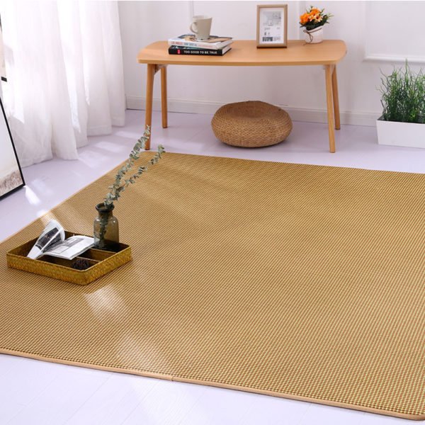 Tapis en rotin de style japonais sur un sol blanc. On voit un plateau posé dessus et une table en arrière plan.