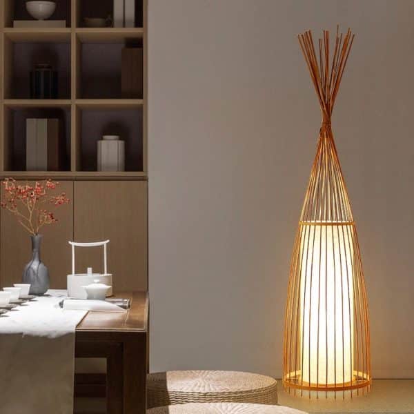 Ce lampadaire est triangulaire. Il est placé dans une salle à manger avec un meuble et une table.