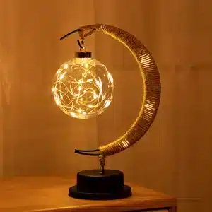 Cette lampe est en forme de lune avec une ampoule ronde. E lle est posée sur une table en bois.