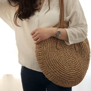 Très joli sac de plage, cabas tissé porté par une femme élégante brune.