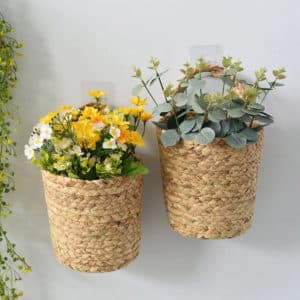 Deux vases suspendus en osier tressé. Ils sont remplis de fleurs des champs.