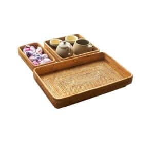 Plateaux de rangement en rotin de trois tailles avec des sachets de thé dans le plus petit et deux tasses et deux théières dans le moyen