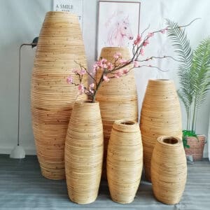 5 grands vases en bambou naturel sont installés les uns à côté des autres, groupés, avec quelques plantes dedans
