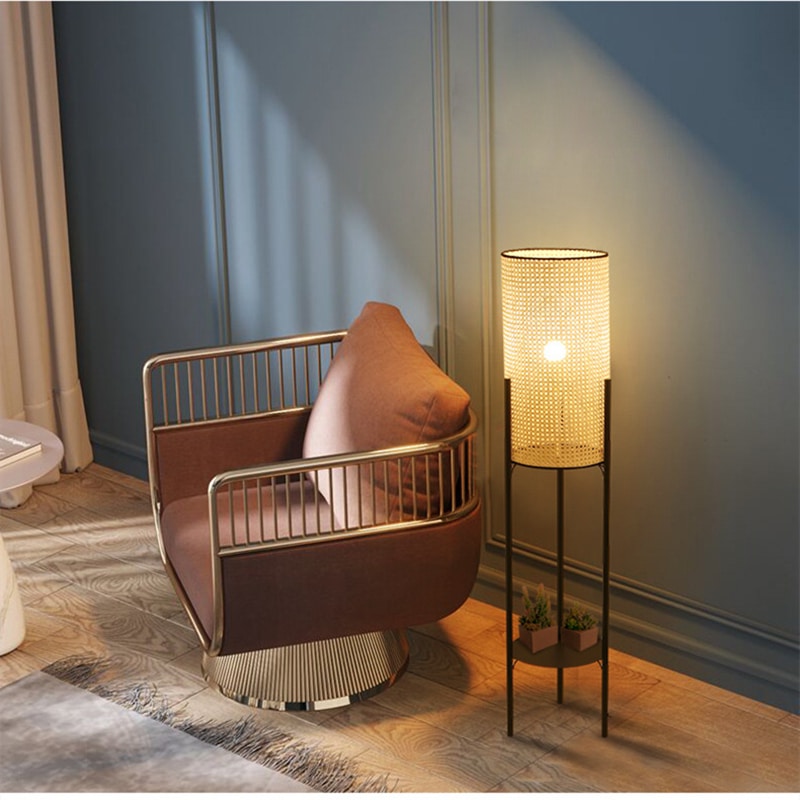 Lampe de bureau moderne en rotin et métal cylindrique sur pieds présenté près d'un fauteuil