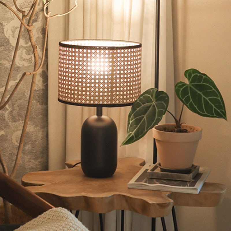 Lampe de bureau LED en rotin avec base noire présenté près d'un pot avec un plante