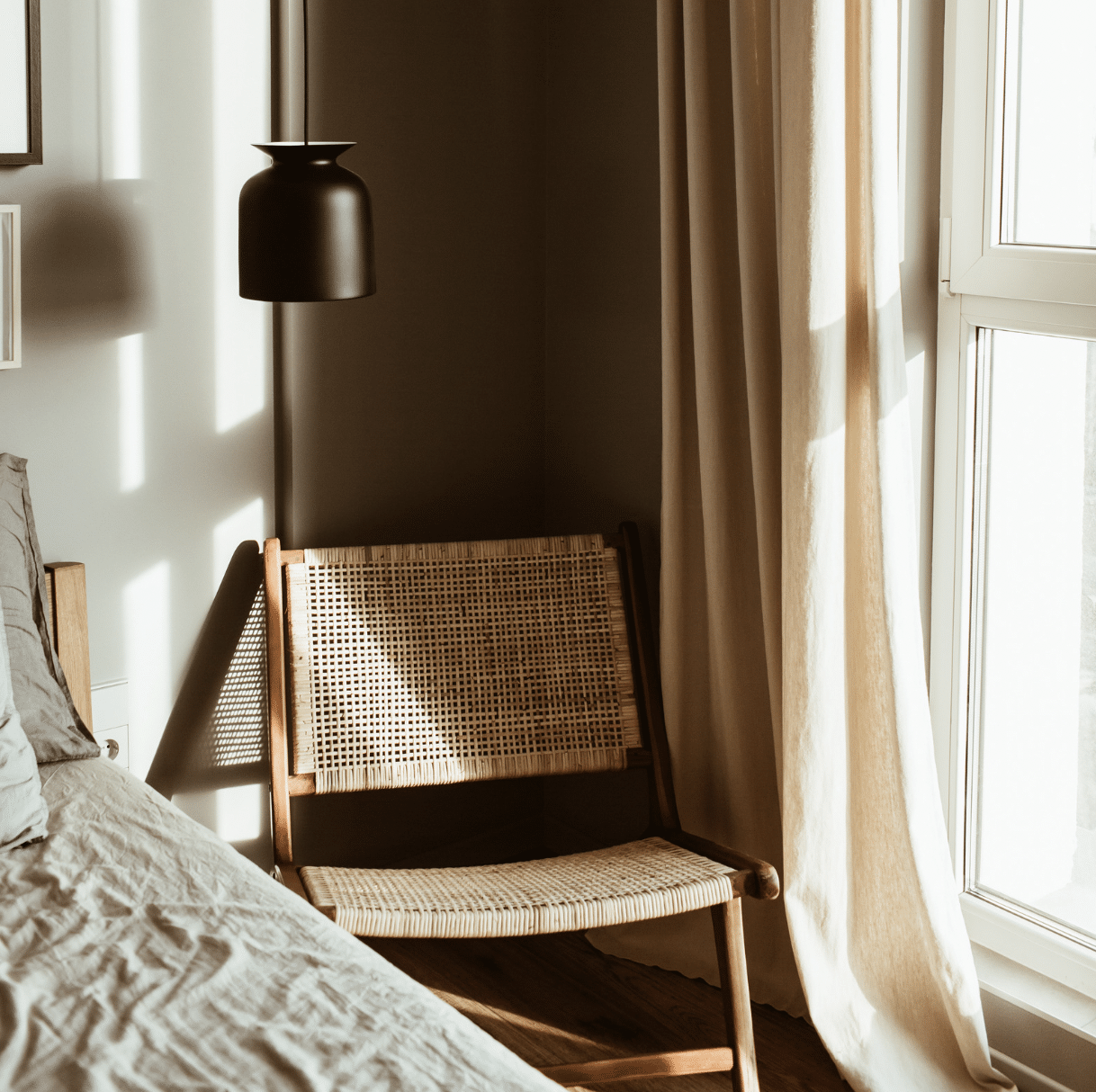 chaise en rotin dans une chambre à côté d'une fenêtre avec un rideau beige