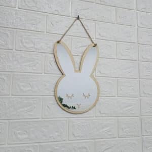Miroir Bois Mural en Forme de Lapin suspendu sur un mur blanc effet brique