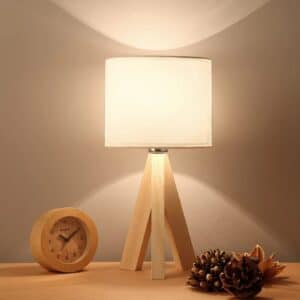 Lampe de Chevet Bois Décorative au Style Contemporain allumée et posée sur une table avec petit réveil à côté
