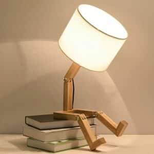 Lampe de Chevet Bois Originale en Forme de Robot allumée et posée sur des livres